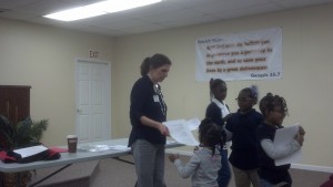 Peletah kids help Mrs. Kelly pass out materials